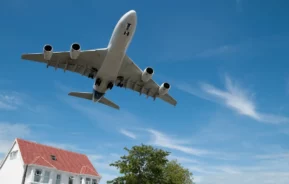 Avião passa por cima de uma casa próxima a um aeroporto.