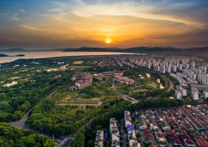 Imagem aérea do por do sol de uma região bem dividida: de um lado, casas residenciais e, outro, vasta floresta com árvores verdes para ilustrar matéria sobre bairro residencial