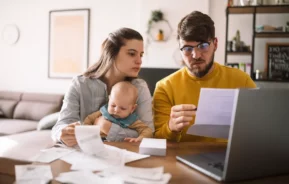 Um homem, sua espeso e filho estão na frente de um computador analisando documentos.