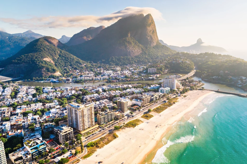 Vista aérea da Barra da Tijuca mostra praia, prédiose morros para ilustrar matéria sobre os bairros nobres do RJ