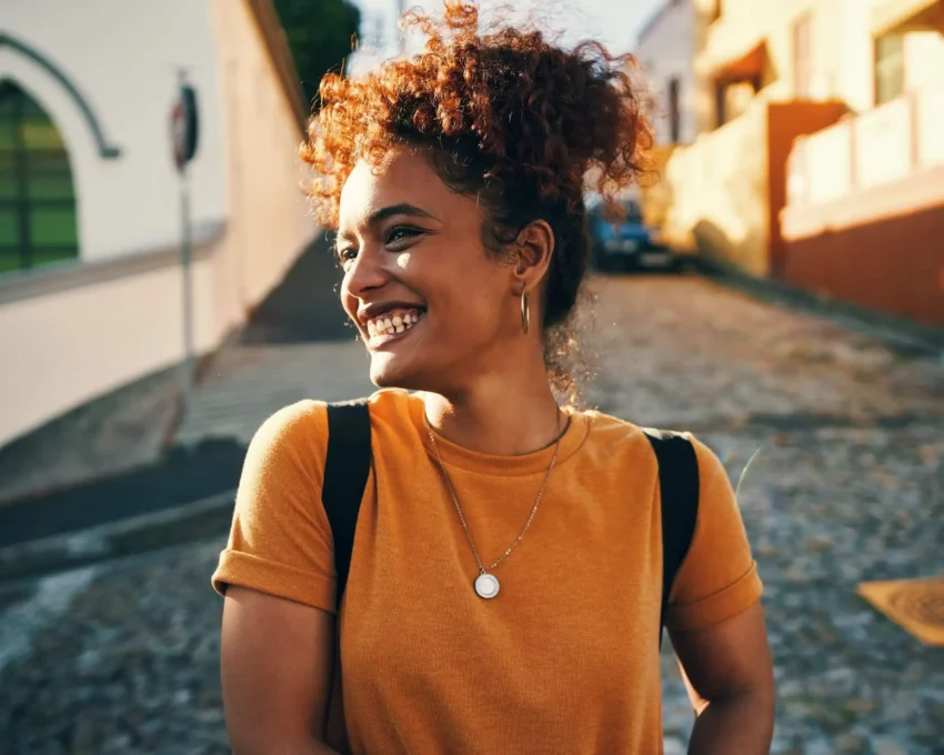 Imagem de uma mulher sorridente andando por uma rua para ilustrar matéria sobre as cidades mais desenvolvidas do Brasil