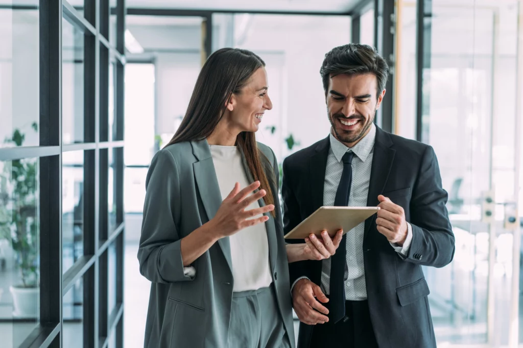 Imagem de uma mulher e um homem em ambiente corporativo conversando enquanto mexem em um tablet para ilustrar matéria sobre quem pode atuar como despachante