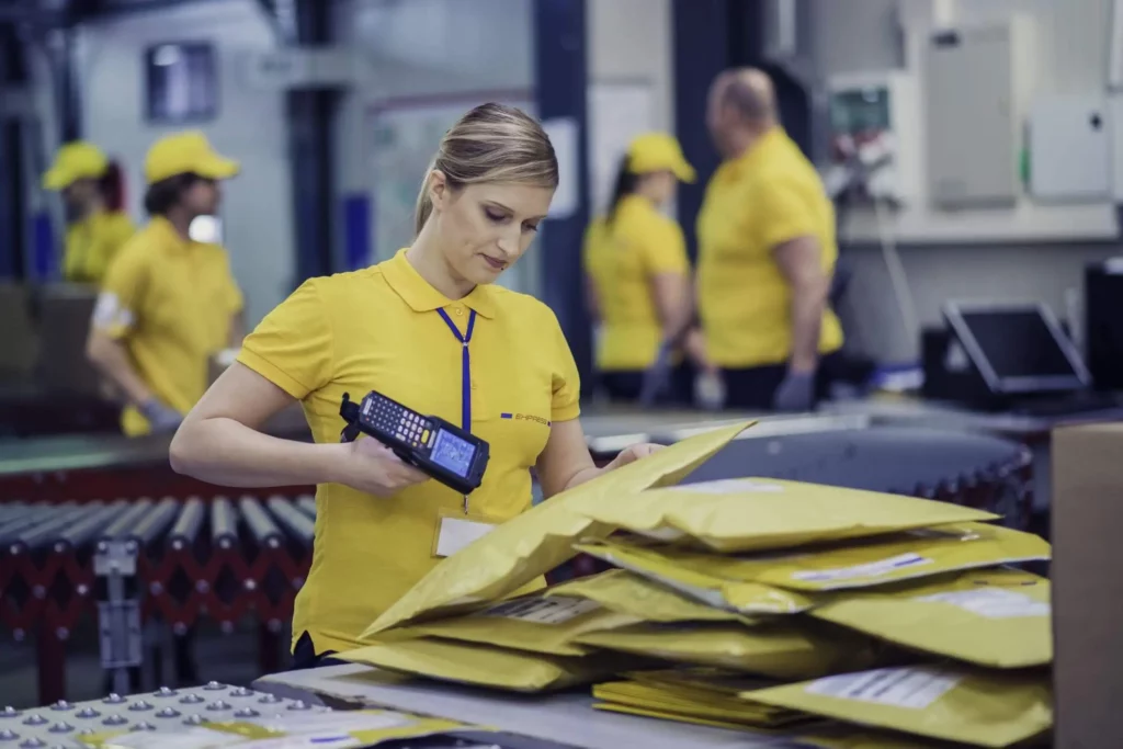 Imagem de uma funcionária dos correios etiquetando pacotes para ilustrar matéria sobre como funciona o código postal (CEP)