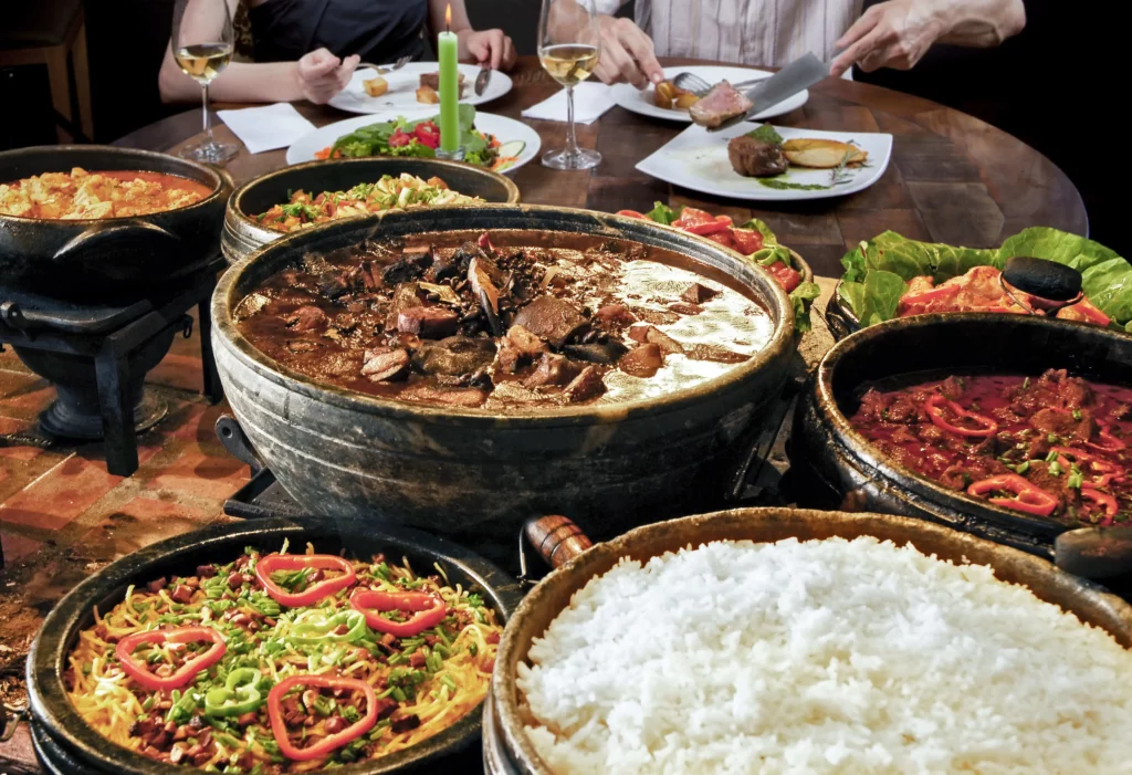 Imagem de comidas brasileiras em primeiro plano e de pessoas comendo em segundo plano para ilustrar matéria sobre onde comer na Zona Sul de Porto Alegre