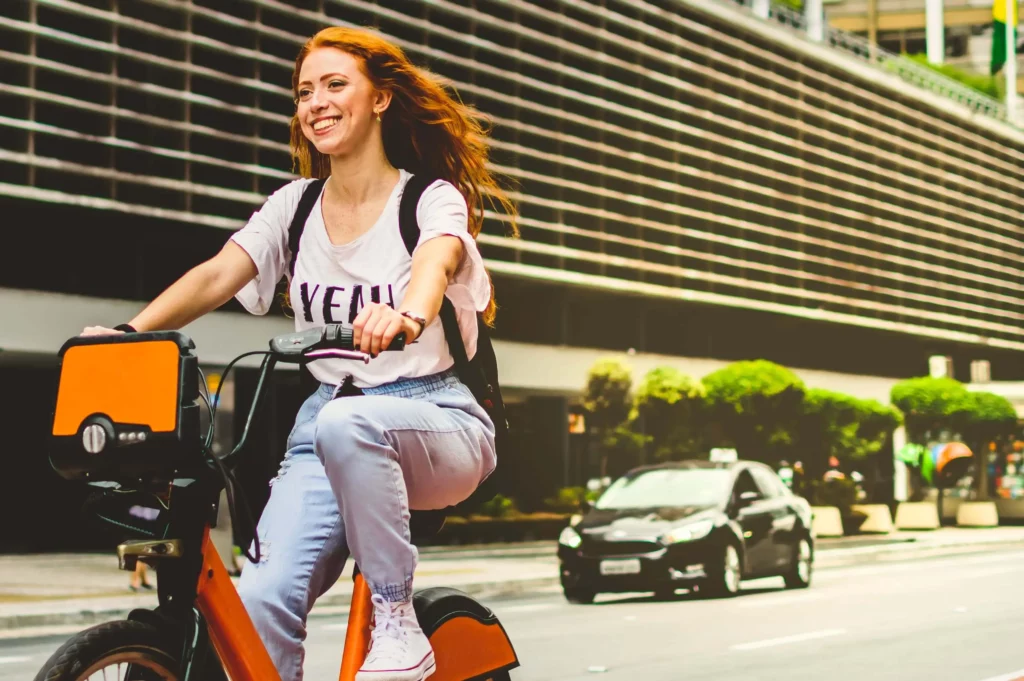 Imagem de jovem mulher sorrindo enquanto anda de bicicleta em São Paulo para ilustrar matéria sobre a Ciclovia Rio Pinheiros