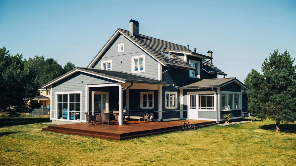 Imagem de uma casa de dois andares na cor cinza em um terreno com grama verde para ilustrar matéria sobre como comprar uma casa sem trabalhar de carteira assinada?