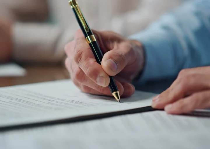 Foto de um homem assinando um documento.