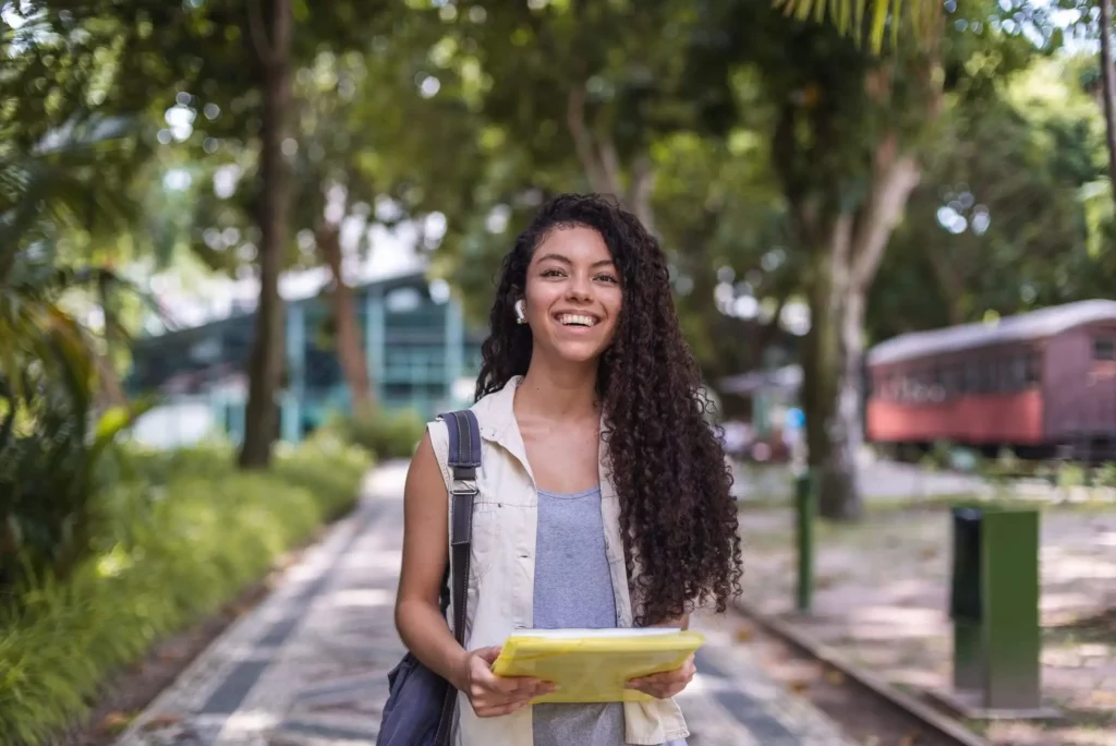 Imagem de uma estudante universitária com uma mochila nas costas e uma pasta nas mãos para ilustrar matéria sobre os bairros mais populosos de Goiânia