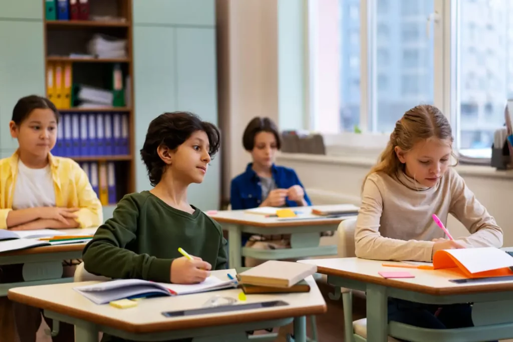 Imagem de uma sala de aula com crianças escrevendo em uma folha de papel para ilustrar matéria sobre conheça as 30 cidades com a melhor educação do Brasil