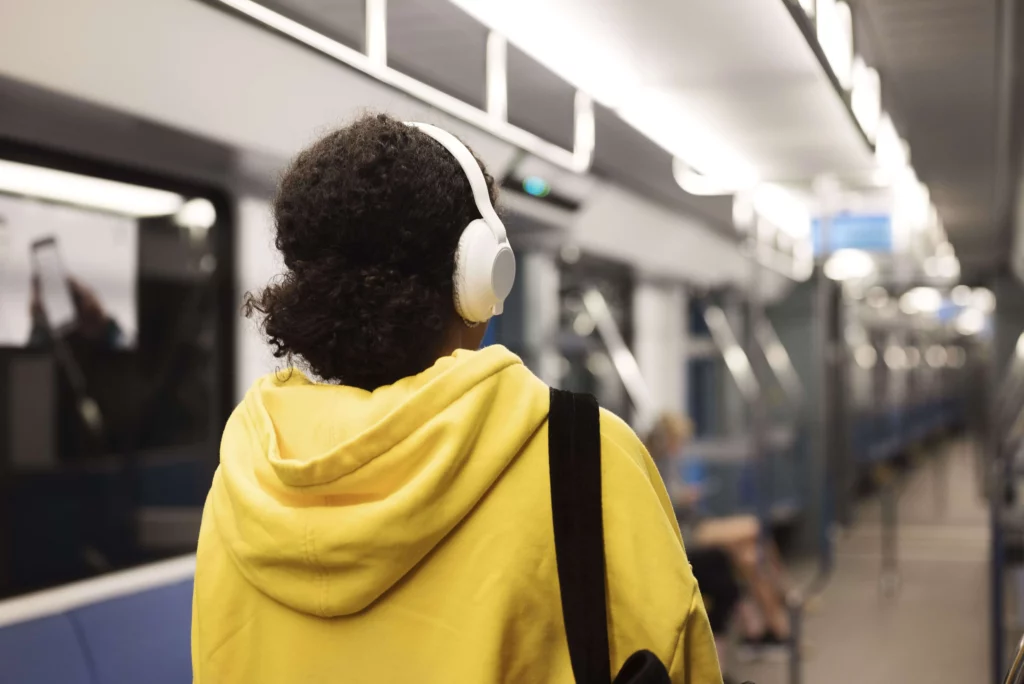 Imagem de uma mulher de costas vestindo um moletom amarelo dentro de um trem do metrô para ilustrar matéria sobre a Linha Lilás