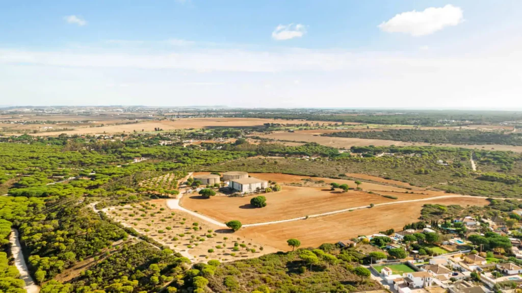 Imagem aérea de um terreno grande com plantações agrícolas e um imóvel ao centro para ilustrar matéria sobre quais são os tipos de arrendamento de imóvel