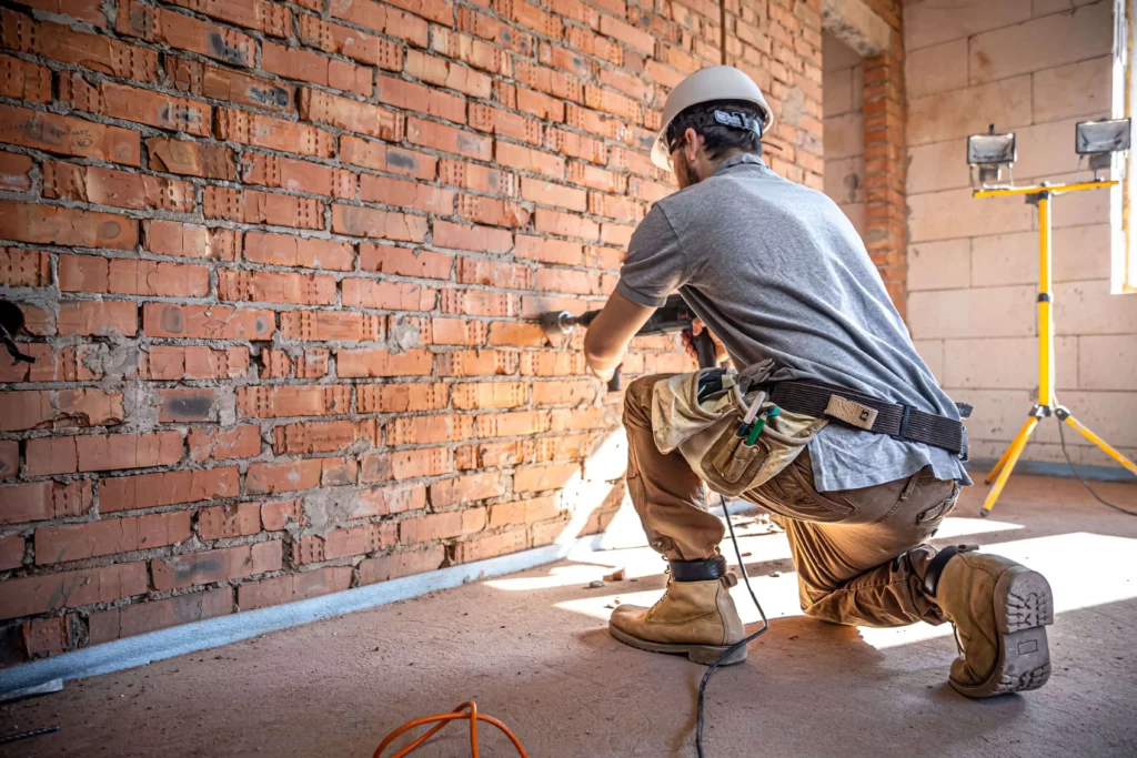 Imagem de um profissional de obras fazendo uma instalação em uma parede de tijolos para ilustrar matéria sobre quais são as restrições de um imóvel tombado