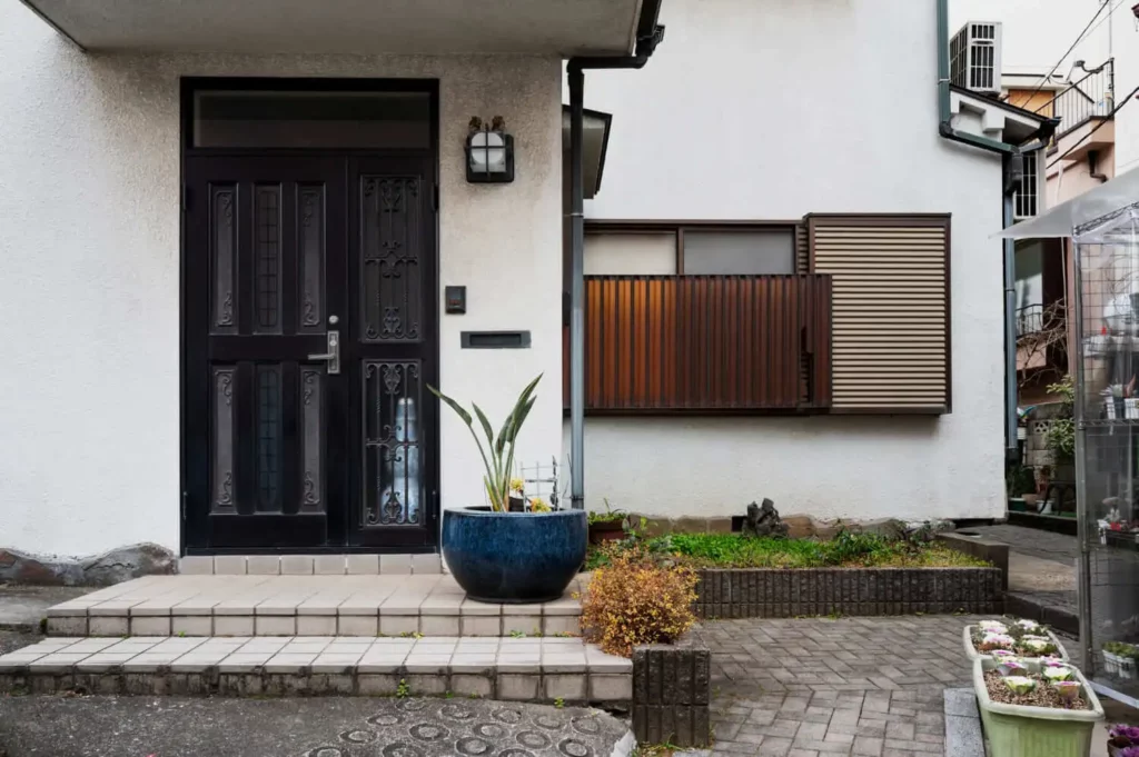 Imagem da fachada externa de uma casa mostra escadas, portas, janelas e plantas da entrada do imóvel para ilustrar matéria sobre construção de casas para alugar